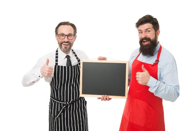 Funcionários do bar café Contratando funcionários Hipster barbudo masculino informando Barman barbudo masculino ou cozinheiro de avental segura lousa em branco Barman com quadro-negro Barman hipster mostra espaço de cópia do quadro-negro