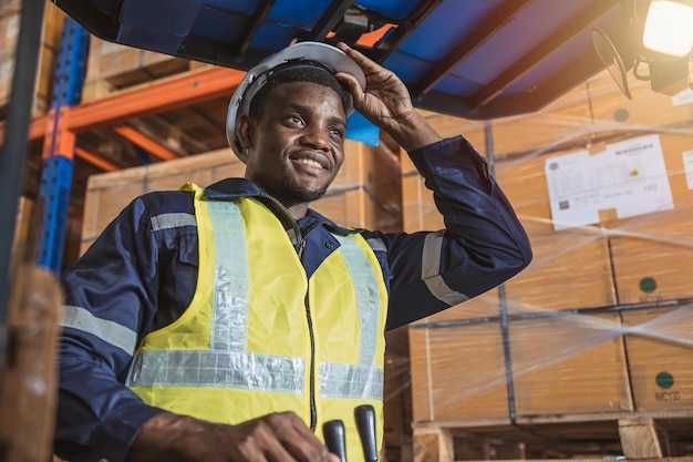 Funcionários negros africanos desfrutam de um trabalho feliz de movimentação de empilhadeiras folclóricas no gerente de estoque do armazém