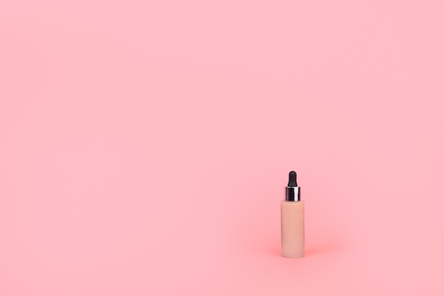 Fundação com mão feminina em fundo rosa BB cream para maquiagem profissional