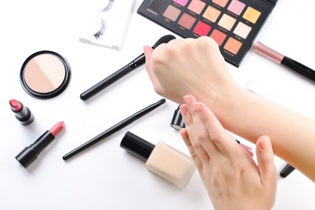 Fundación en manos de mujer Productos de maquillaje profesional con productos de belleza cosmética base lápiz labial sombras de ojos pestañas cepillos y herramientas