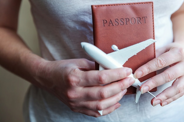 Fundamentos turísticos. Mulher feminina com as mãos segurando um pequeno avião modelo de brinquedo e um passaporte