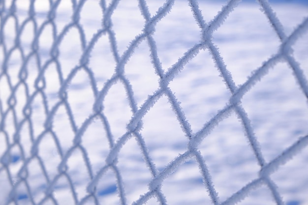 Foto fundo, a rede está coberta de geada e neve em um dia gelado de inverno.