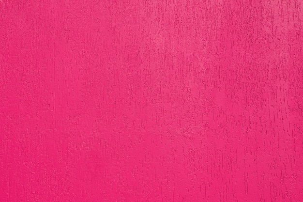 Fundo abstrato e textura de uma parede emplastrada da cor rosa brilhante com textura de besouro de casca. iluminado pelo sol brilhante.