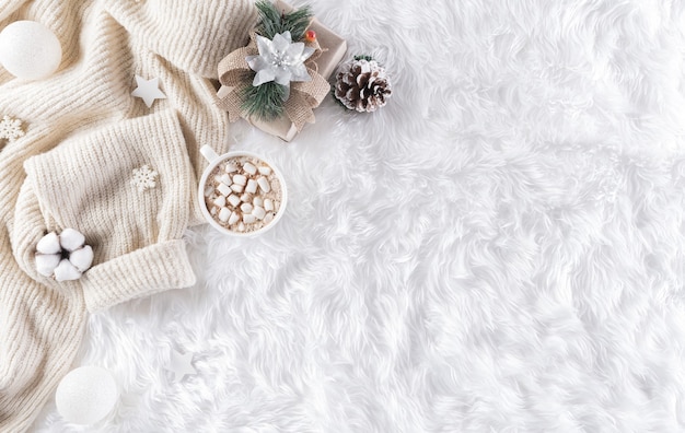 Fundo aconchegante de inverno com xícara de café, agasalho quente, caixa de presente, flor de algodão e bola de natal