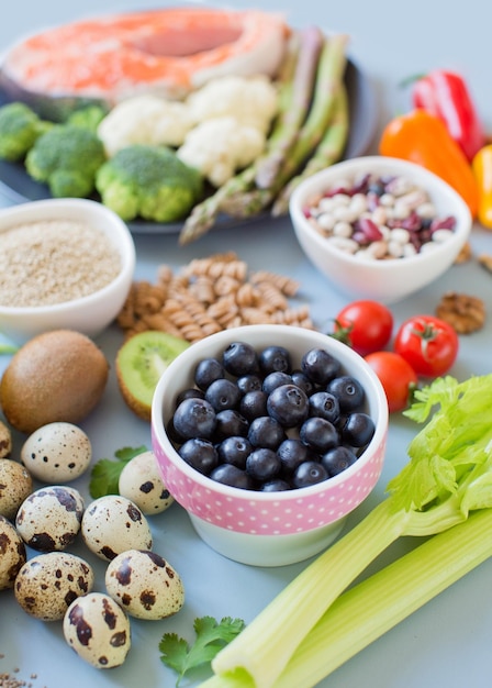 Fundo alimentar de dieta equilibrada Legumes frescos frutas cereais sementes e nozes em um fundo azul