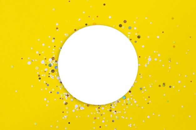 Foto fundo amarelo com uma maquete redonda branca no centro com brilho de confete dourado ao redor