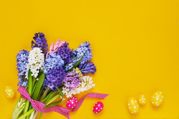 Fundo amarelo da Páscoa. Flores da primavera e ovos de Páscoa decorativos em fundo amarelo. Copie o espaço