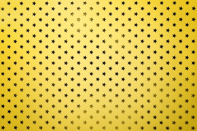 Fundo amarelo de papel de folha de metal com um padrão de estrelas douradas