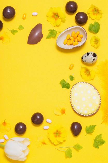 Fundo amarelo de Páscoa com ovos de chocolate, doces e spri