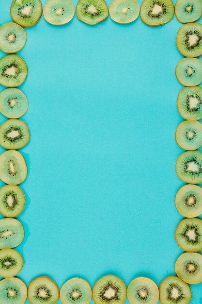 Foto fundo azul brilhante e moldura feita de fatias finas e suculentas de kiwi