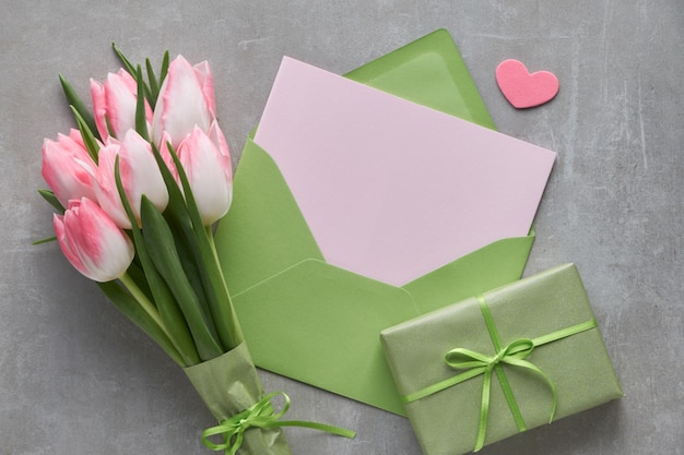 Fundo azul da primavera com tulipas cor de rosa, caixa de presente embrulhada e corações decorativas