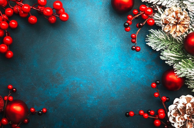 Fundo azul de Natal ou Ano Novo com bolas de Natal vermelhas, bagas de abeto, galhos de pinheiro, vista superior