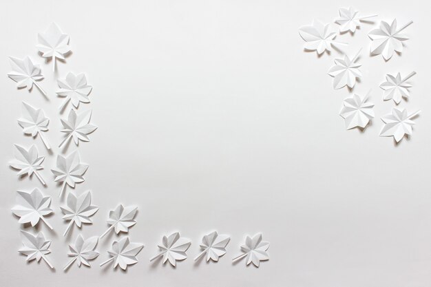 Foto fundo branco com folhas de bordo de origami dobradas de papel branco dispostas nos cantos. imagem com espaço em branco de cópia.