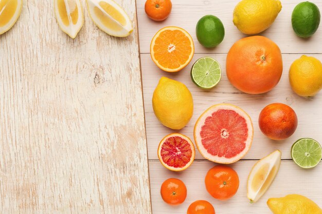 Fundo cítrico. Laranjas, limões, toranjas e outras frutas antioxidantes em madeira branca. Estilo de vida saudável, conceito de vitaminas naturais, vista superior, cópia espaço na velha tábua de corte rústica, postura plana