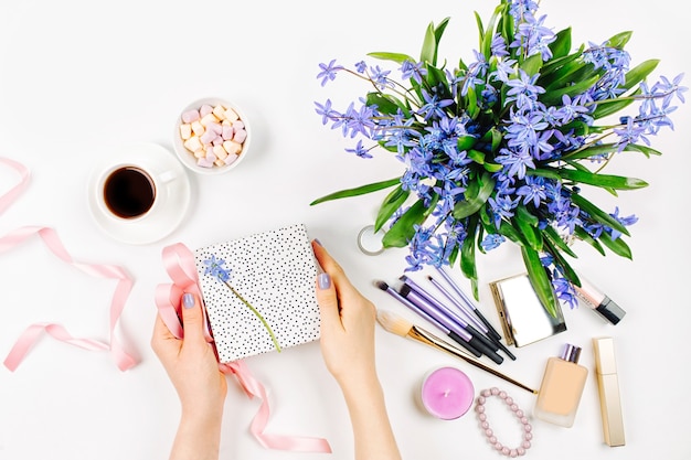 Fundo com buquê de primavera azul, bombons e acessórios cosméticos