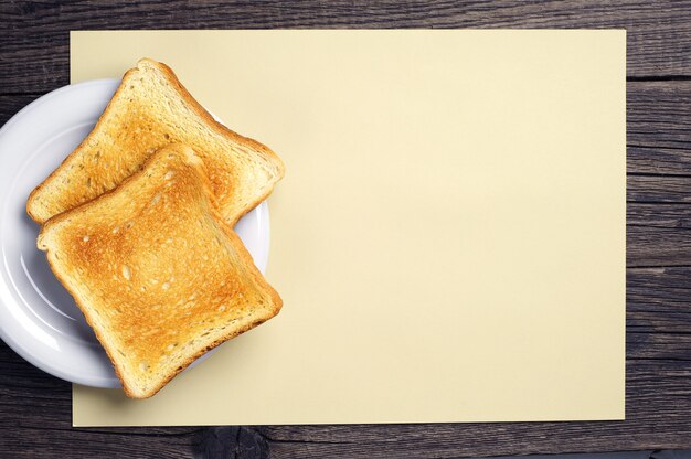 Fundo com fatias de pão torrado e folha de papel amarelo em branco