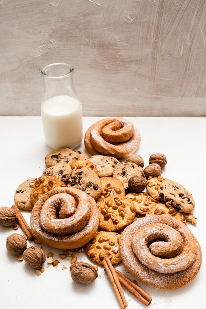 Fundo culinário do café da manhã orgânico de pastelaria, close-up do espaço livre. scones integrais e pãezinhos assados com nozes e canela perto da garrafa de leite. conceito de loja caseira