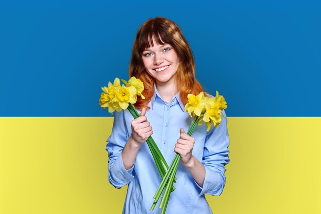 Fundo da bandeira da Ucrânia jovem sorridente linda mulher segurando flores amarelas