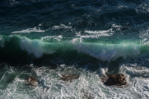 Fundo da onda do oceano quebrando a costa rochosa da água do mar