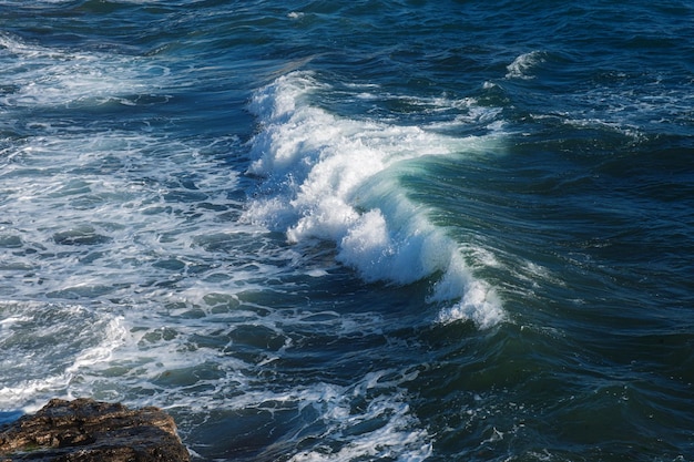Fundo da onda do oceano quebrando a costa rochosa da água do mar
