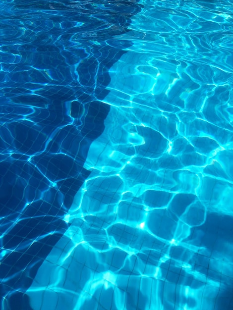 Fundo de água, ondulação e fluxo com ondas. Piscina azul de verão.