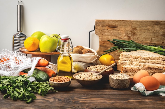 Fundo de alimentos, legumes, frutas e cereais em uma mesa de madeira na cozinha, ingredientes de cozinha saudáveis.