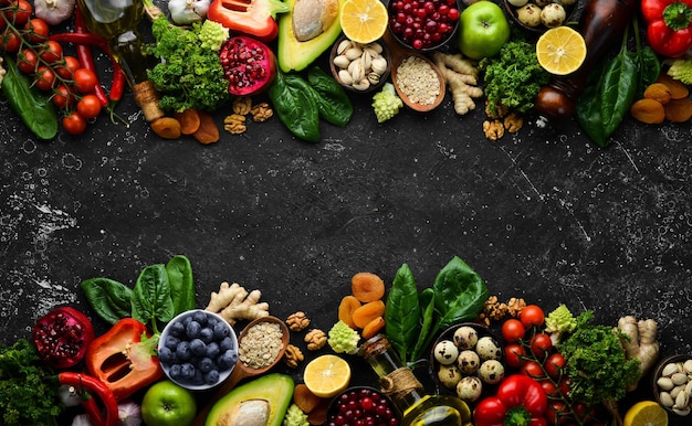 Fundo de alimentos Um conjunto de vegetais de alimentos saudáveis e limpos frutas carne de peixe nozes e verduras Em um fundo de pedra preta Vista superior Espaço para cópia grátis