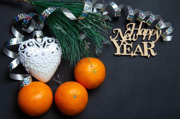 Fundo de ano novo de véspera de ano novo com laranjas e acessórios de ano novo em um fundo escuro