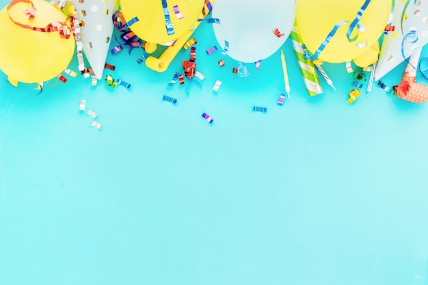 Fundo de balão de aniversário com serpentinas coloridas, confetes e chapéus de festa de aniversário em azul