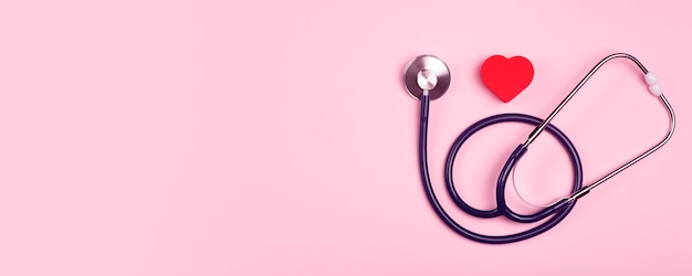 Fundo de banner do dia mundial do coração. Coração como um símbolo de saúde, tratamento, caridade, doação e cardiologia em um fundo rosa com um estatoscópio médico.