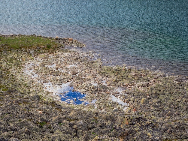 Fundo de bela natureza de fundo pedregoso na água transparente turquesa do lago glacial na luz solar. Pano de fundo ensolarado com muitas pedras nas águas claras turquesa do Lago glaciar.