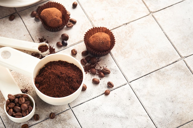 Fundo de café colheres de medição com xícara de grãos de café moído e trufas de chocolate doce no fundo da mesa rachada de azulejos antigos fundo de alimentos vista superior com espaço para o seu texto