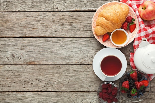 Fundo de café da manhã delicioso. Saborosos croissants, muesli e frutas orgânicas doces frescas para refeições matinais na mesa de madeira rústica com espaço de cópia. Vista superior sobre nutrição diária rica