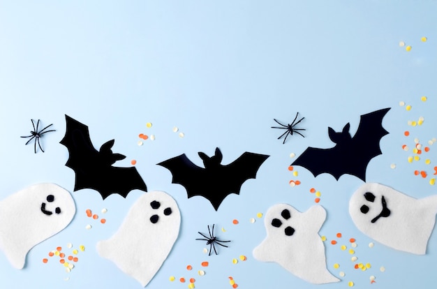 Fundo de cartão de festa de Halloween com decoração, fantasma, aranhas e morcego no fundo azul, vista superior