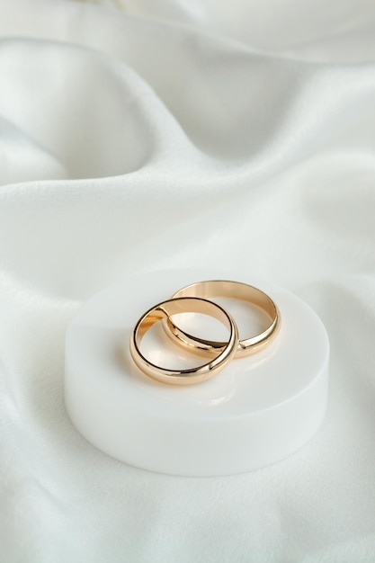 Fundo de casamento com dois anéis de ouro em material de cetim branco Casamento