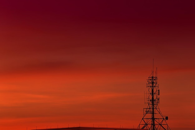 Fundo de céu vermelho e laranja com silhueta de torre de telefone