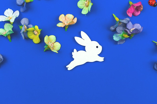 Fundo de coelhinho da páscoa, composição plana leiga com flores da primavera em um fundo azul