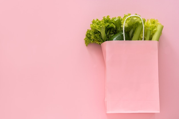 Foto fundo de comida saudável de entrega. comida vegetariana vegana em vegetais de saco de papel em fundo rosa. supermercado de comida de compras de supermercado e conceito de alimentação limpa. vista superior.