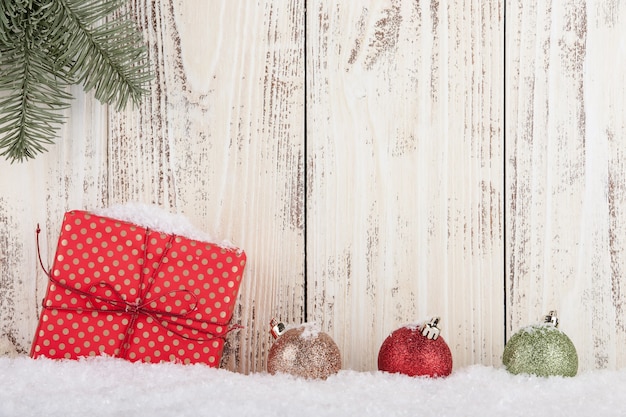 Fundo de conceito de Natal e Ano Novo com caixa de presente e bolas de Natal na neve