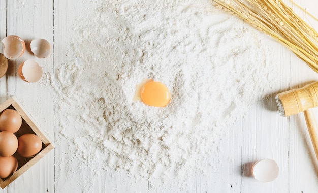 Foto fundo de cozimento com ingredientes do bolo em madeira branca acima de ovos de farinha de tigela