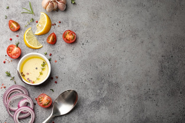 Fundo de cozimento de alimentos na mesa rústica de pedra cinza com ingredientes frescos, vegetais, ervas, especiarias, azeite e colher de cozinha de cima com espaço para texto