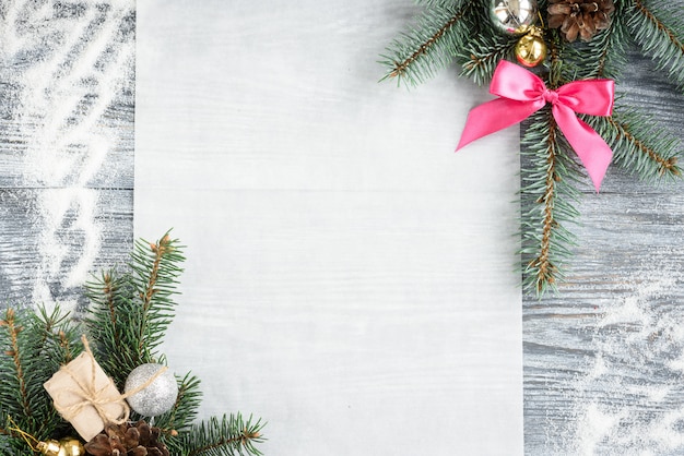 Fundo de decoração de natal ou ano novo com galhos de pinheiro, cones, bolas, marshmallows na placa de madeira cinza.