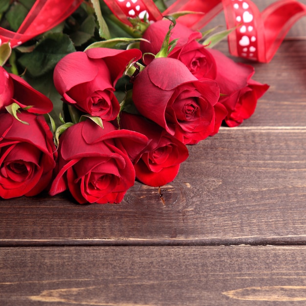 Foto fundo de dia dos namorados de rosas vermelhas e fita na madeira