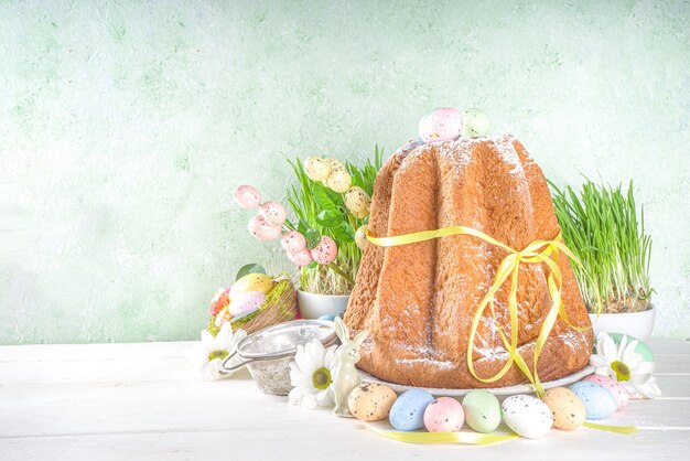 Fundo de doces e decorações de Páscoa, panetone de bolo de Páscoa doce com ovos pintados de cores, grama e decoração de primavera, espaço de cópia para texto