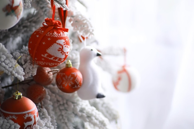 Fundo de férias de natal. bugiganga de prata e cor pendurada em uma árvore decorada com bokeh e neve, copie o espaço.