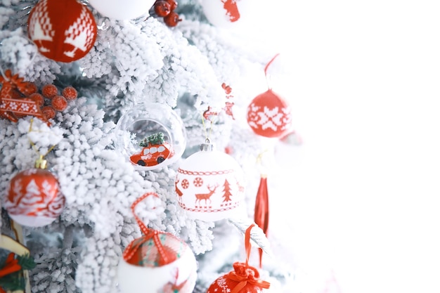 Fundo de férias de natal. bugiganga prateada e colorida pendurada em uma árvore decorada com bokeh e neve, copie o espaço.