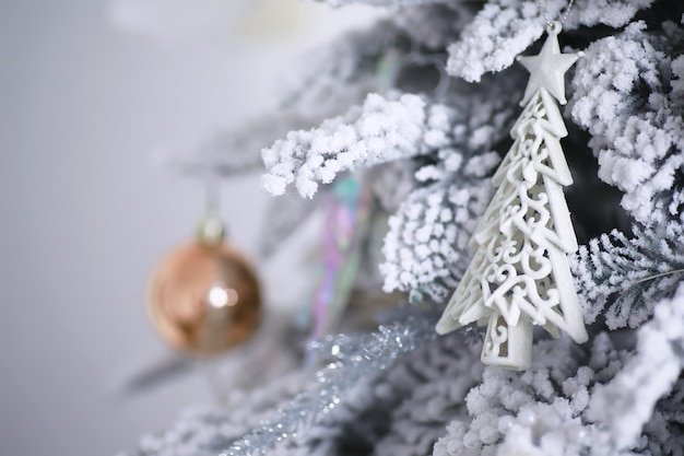 Fundo de férias de natal. bugiganga prateada e colorida pendurada em uma árvore decorada com bokeh e neve, copie o espaço.