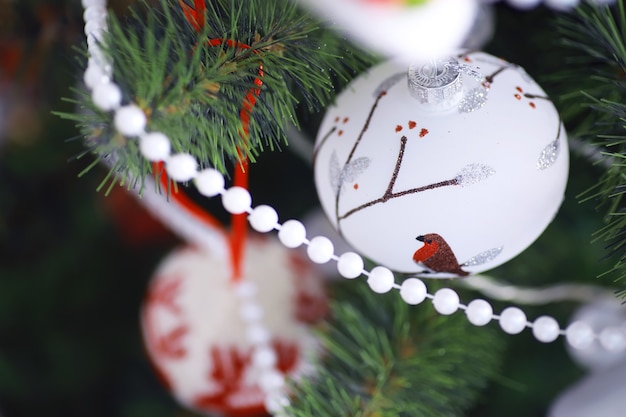 Fundo de férias de Natal. Bugiganga prateada e colorida pendurada em uma árvore decorada com bokeh e neve, copie o espaço.