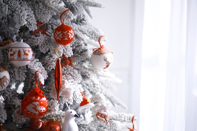 Fundo de férias de Natal. Bugiganga prateada e colorida pendurada em uma árvore decorada com bokeh e neve, copie o espaço.