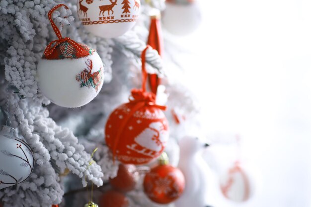 Fundo de férias de Natal. Bugiganga prateada e colorida pendurada em uma árvore decorada com bokeh e neve, copie o espaço.